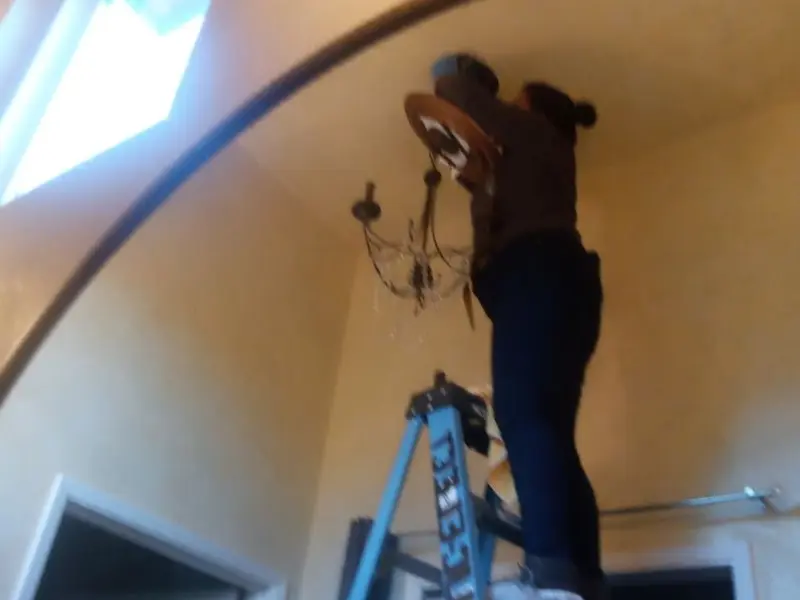 Electrician installing a chandelier in a University residence